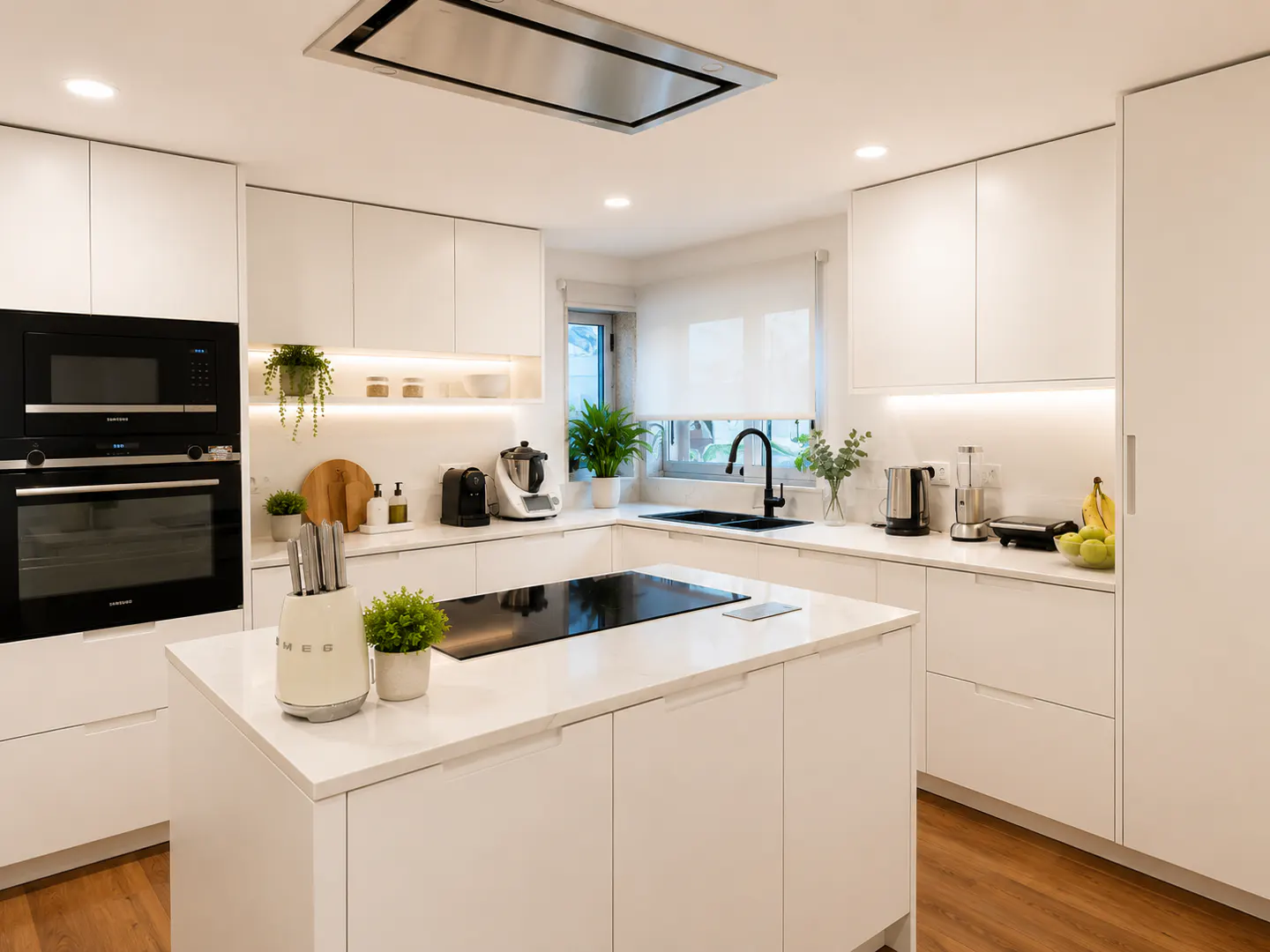 Bright, modern kitchen with white cabinets, island with black cooktop, and stainless steel appliances. Wood floor and natural light.