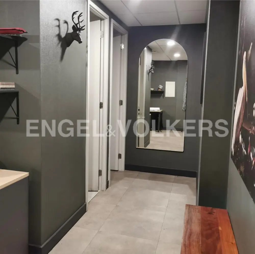 Hallway with gray walls, light tile floor, and white doors. A deer head wall decoration and arched mirror add visual interest.