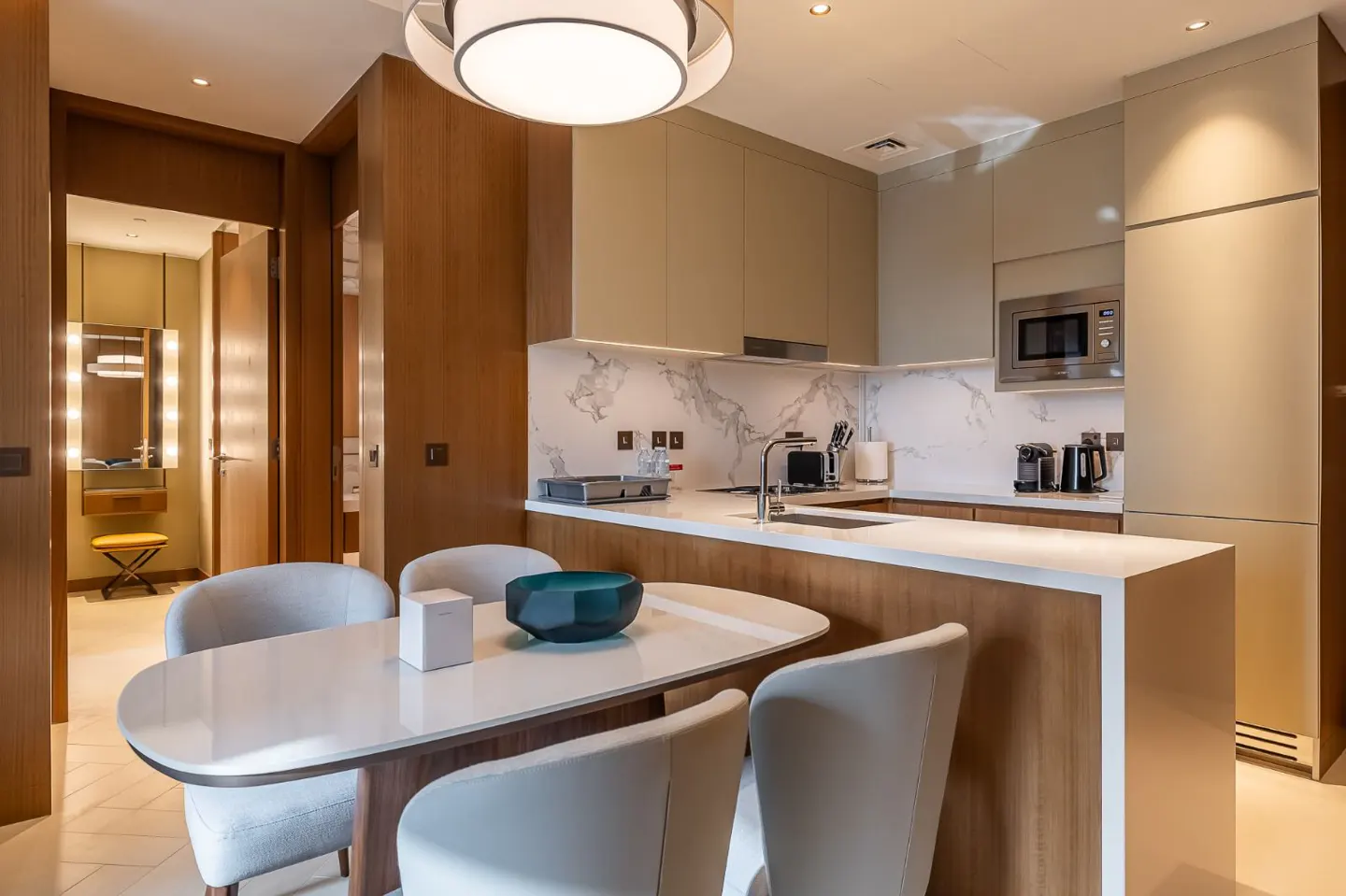 A modern kitchen with a white countertop, light brown cabinets, and a dining table with four chairs.
