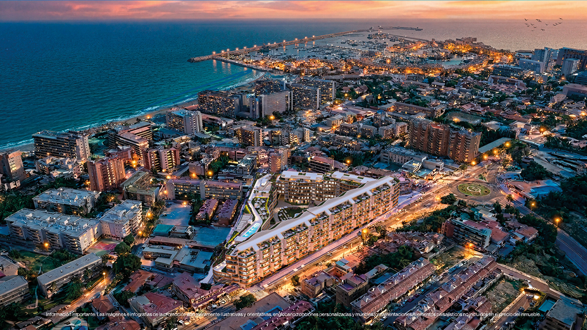 Aerial view of a modern apartment complex at twilight, overlooking a coastal city, harbor, and the Mediterranean Sea.