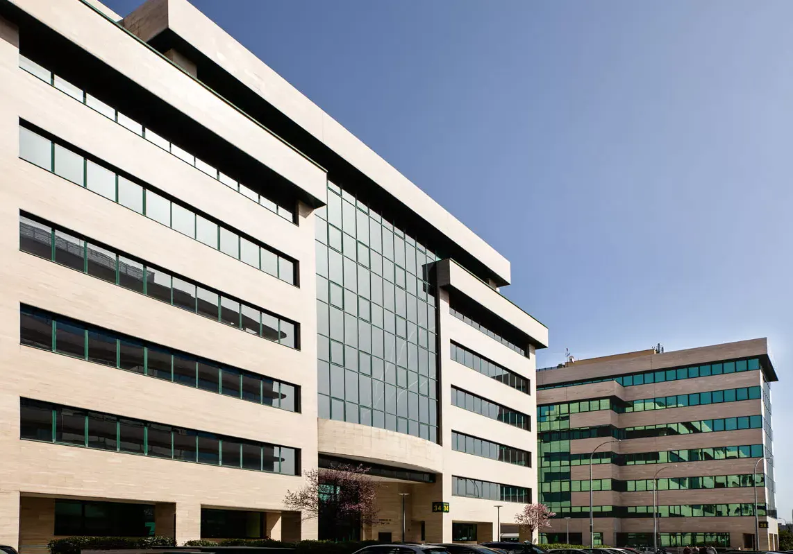 Exterior view of two modern office buildings with glass windows and a clear blue sky.