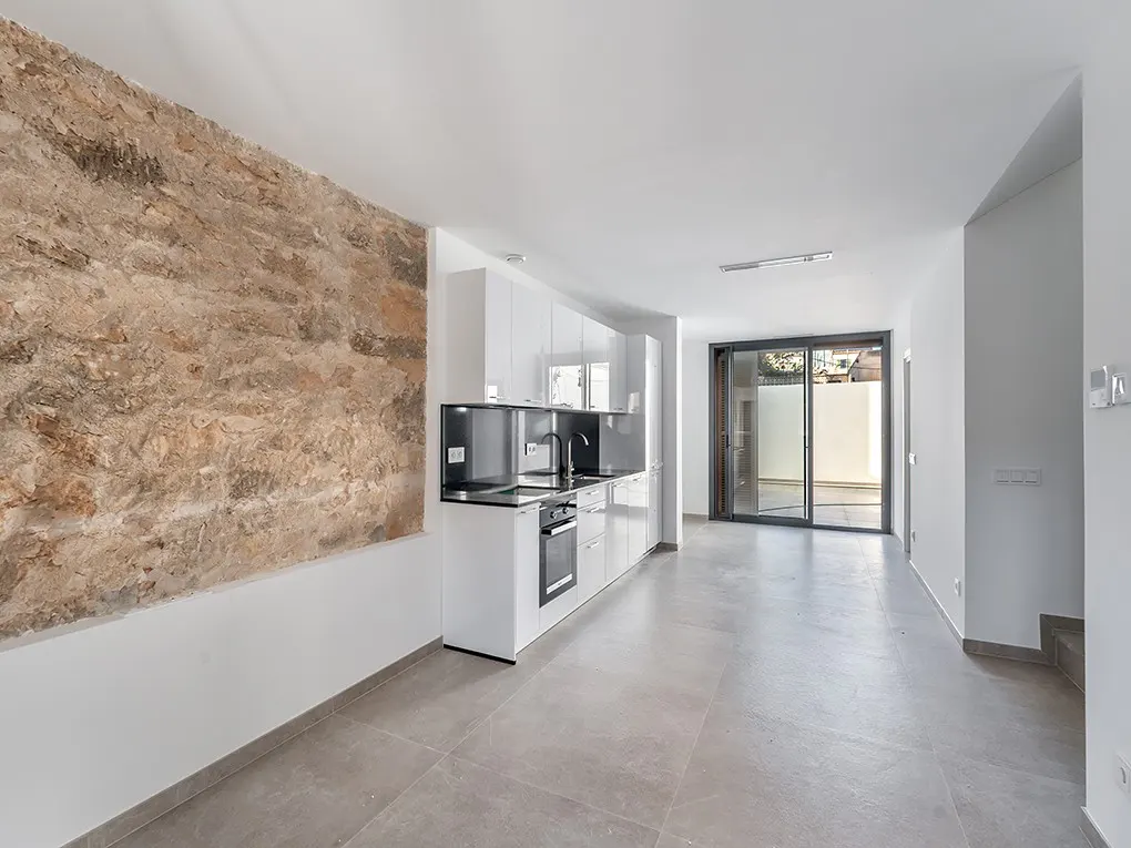 Bright, modern apartment with a stone accent wall, white cabinets, and sliding glass doors to a patio.