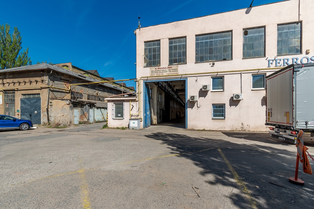 Exterior view of a warehouse with a truck parked outside, featuring large windows and a loading dock.