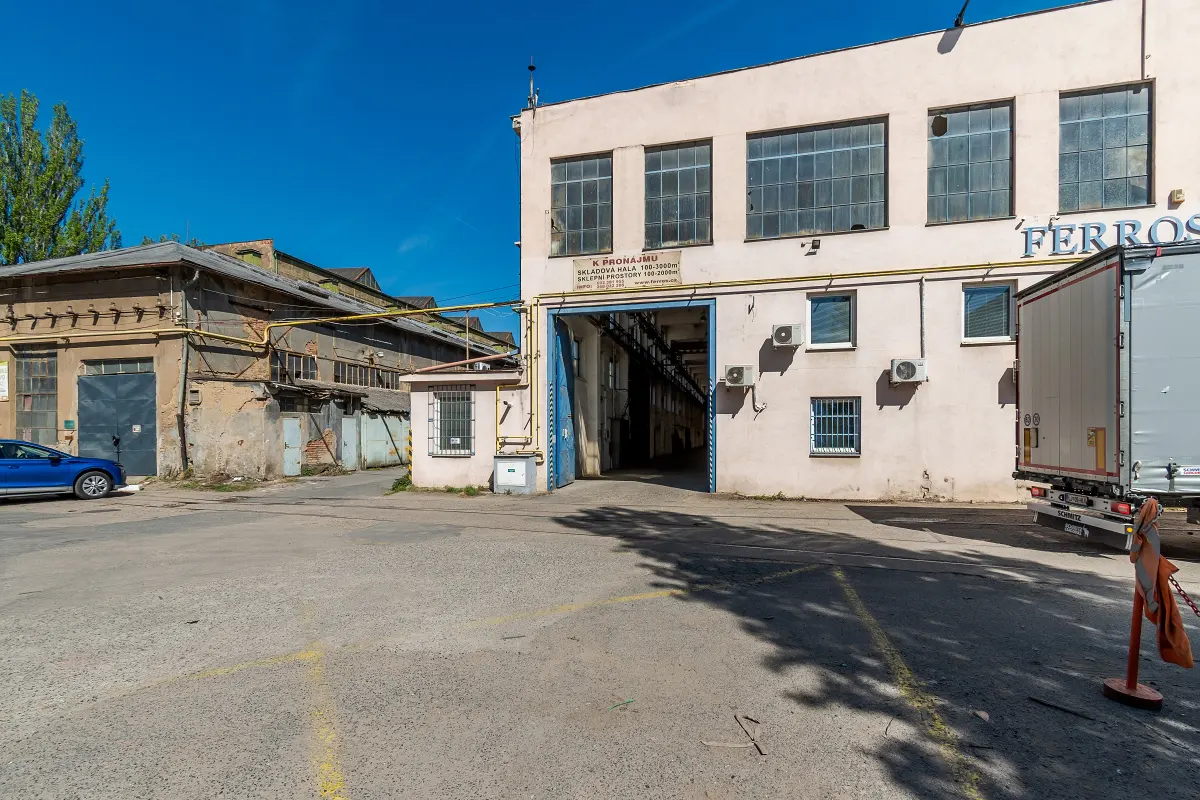 Exterior view of a warehouse with a truck parked outside, featuring large windows and a loading dock.