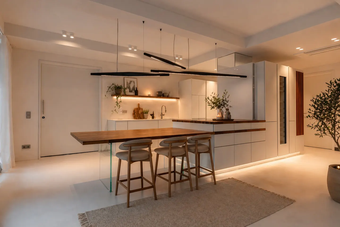 Bright, modern kitchen with white cabinets, wood island with stools, and linear pendant lights. A rug sits on the white floor.