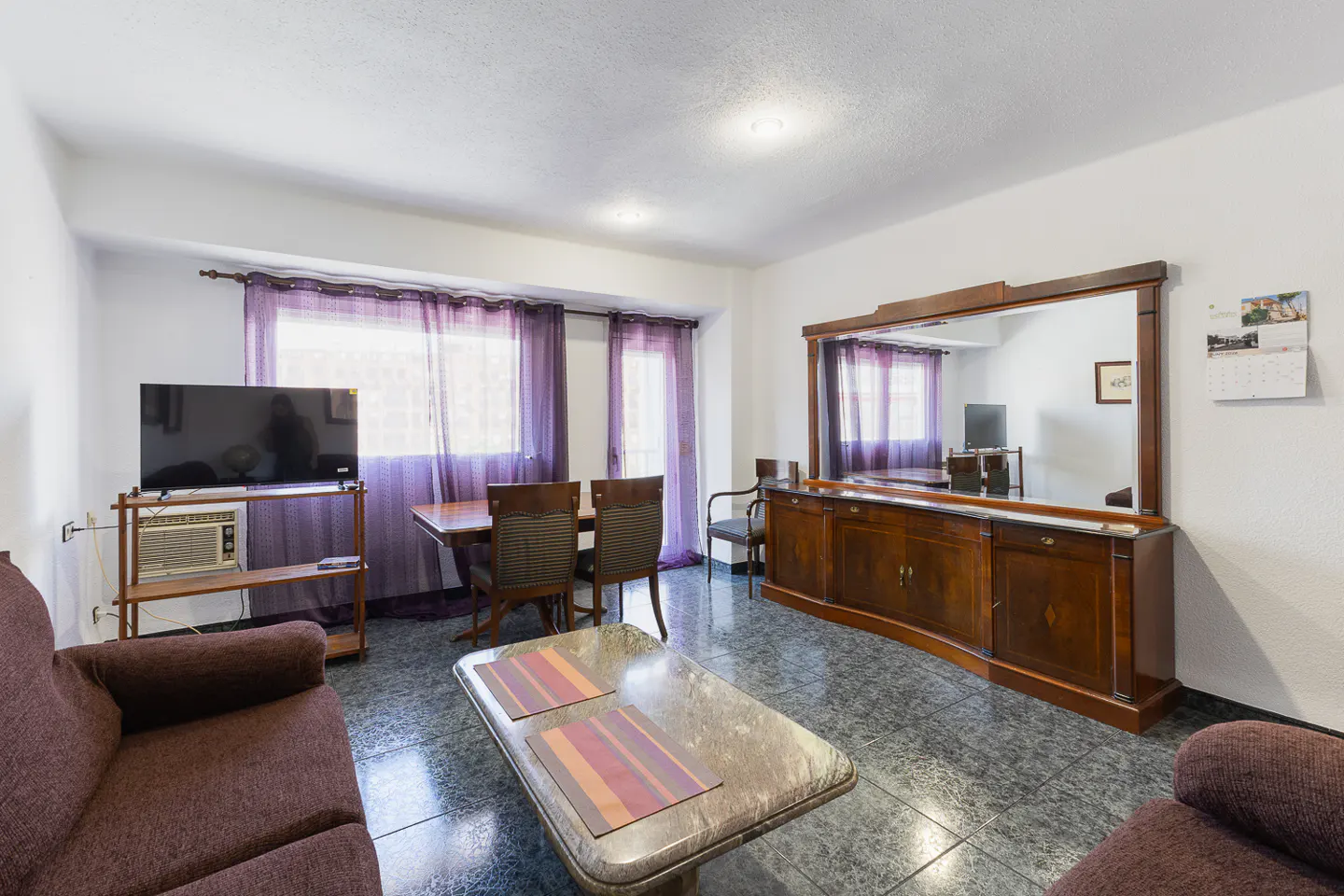 Living room with brown sofas, a marble coffee table, a wooden dining set, and a large sideboard with a mirror.