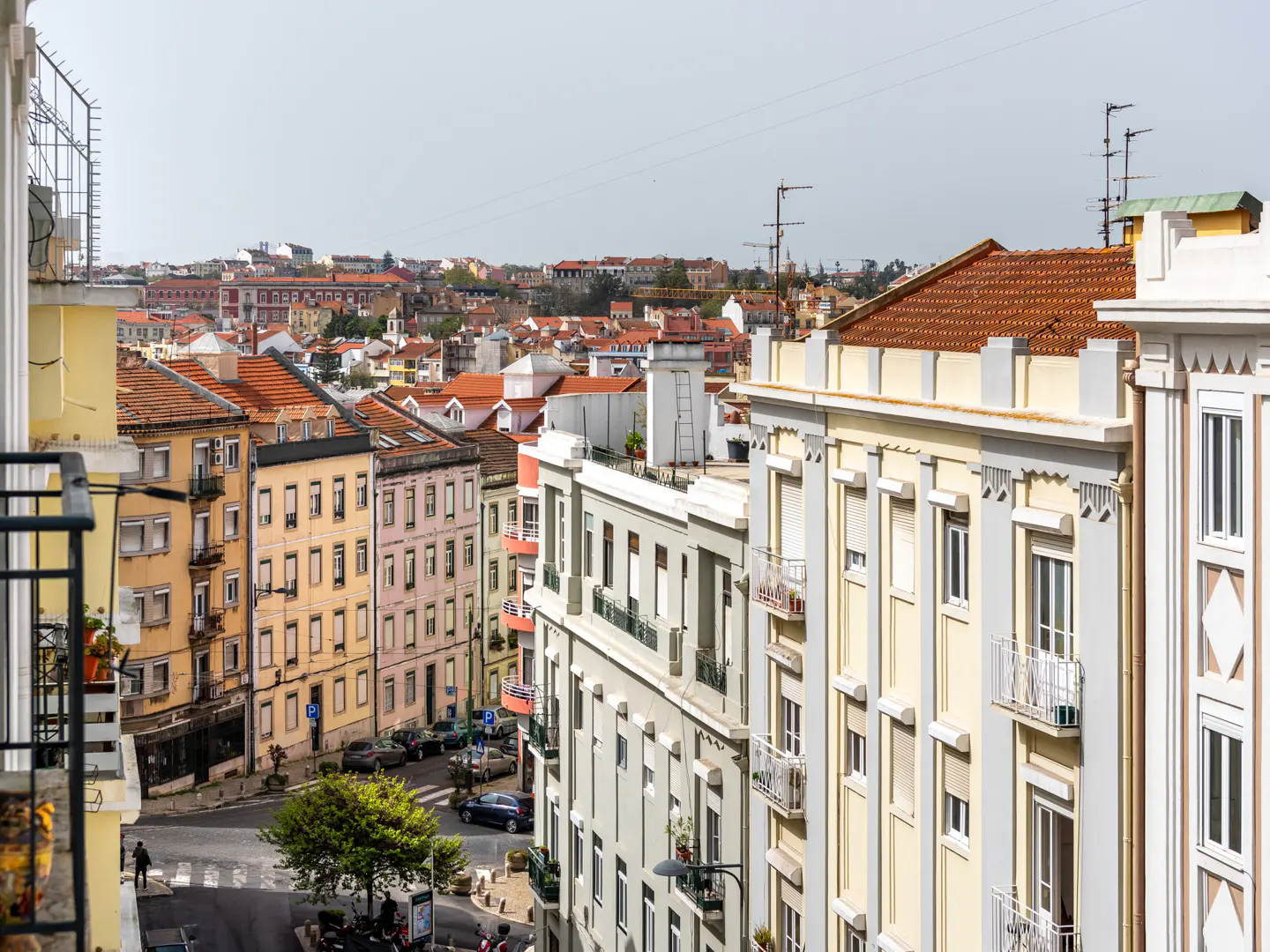 High-angle view of a European city street with colorful historic buildings, balconies, and terracotta rooftops.