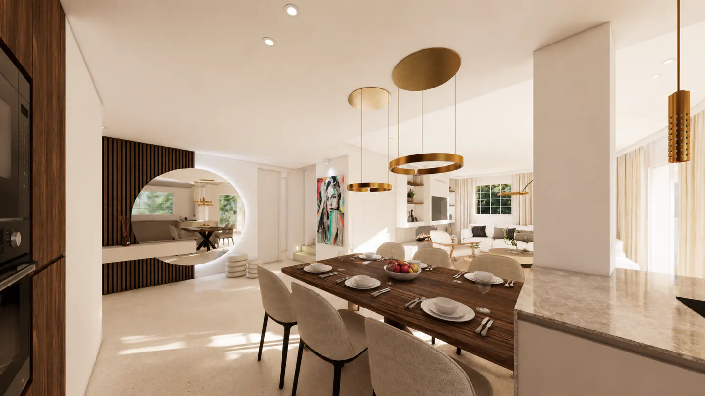 Bright, modern dining room with a long wooden table, beige chairs, and gold pendant lights. A circular opening leads to a seating area.