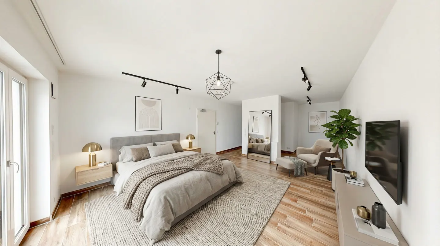 A bright bedroom with a gray bed, beige rug, and wooden floors. A geometric light fixture hangs from the ceiling. A TV and chair are visible in the background.