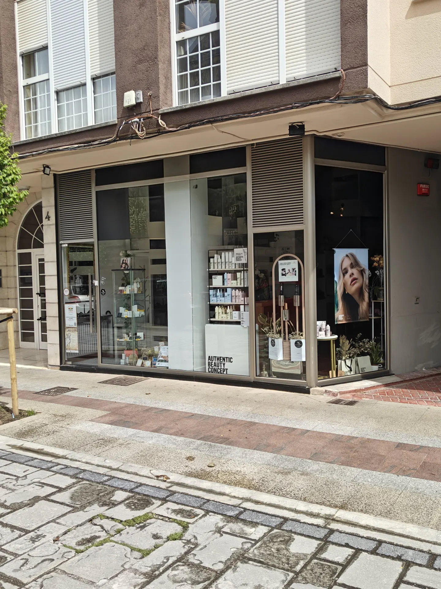 Storefront view of "Authentic Beauty Concept" with product displays and a blonde model poster in the window.