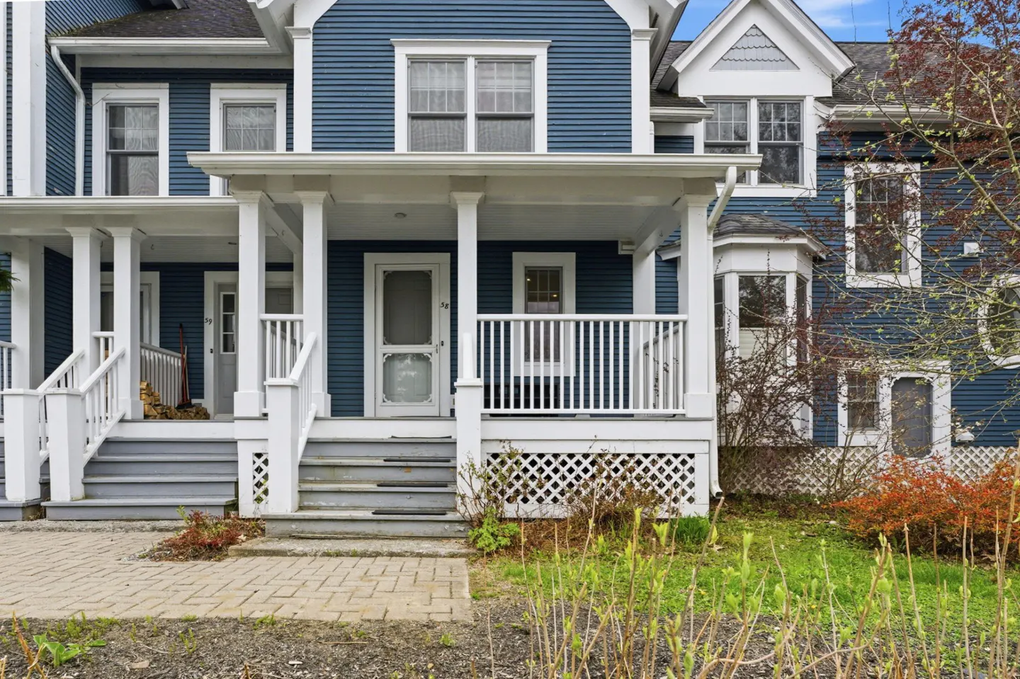 Exterior view of blue townhouses with white trim, porches, and brick walkway.