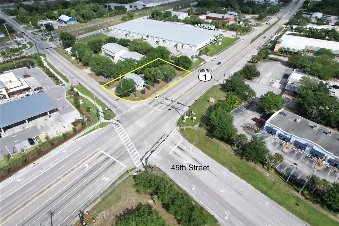 Aerial view of a property outlined in yellow at the intersection of 45th Street and Route 1, surrounded by trees and commercial buildings.