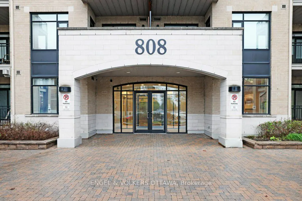 Exterior view of a building entrance with the number 808 above the arched doorway and a brick walkway.