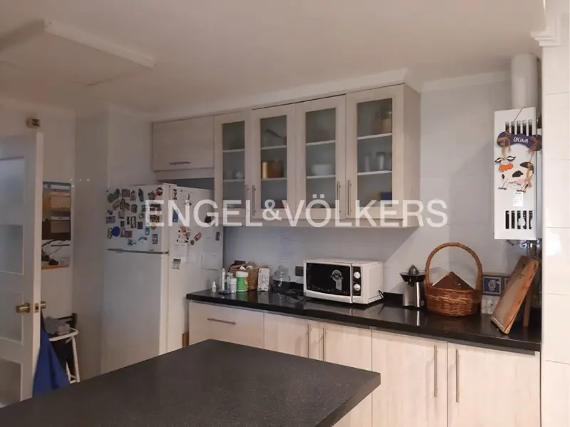 Kitchen with light wood cabinets, black countertops, white refrigerator with magnets, and a microwave on the counter.