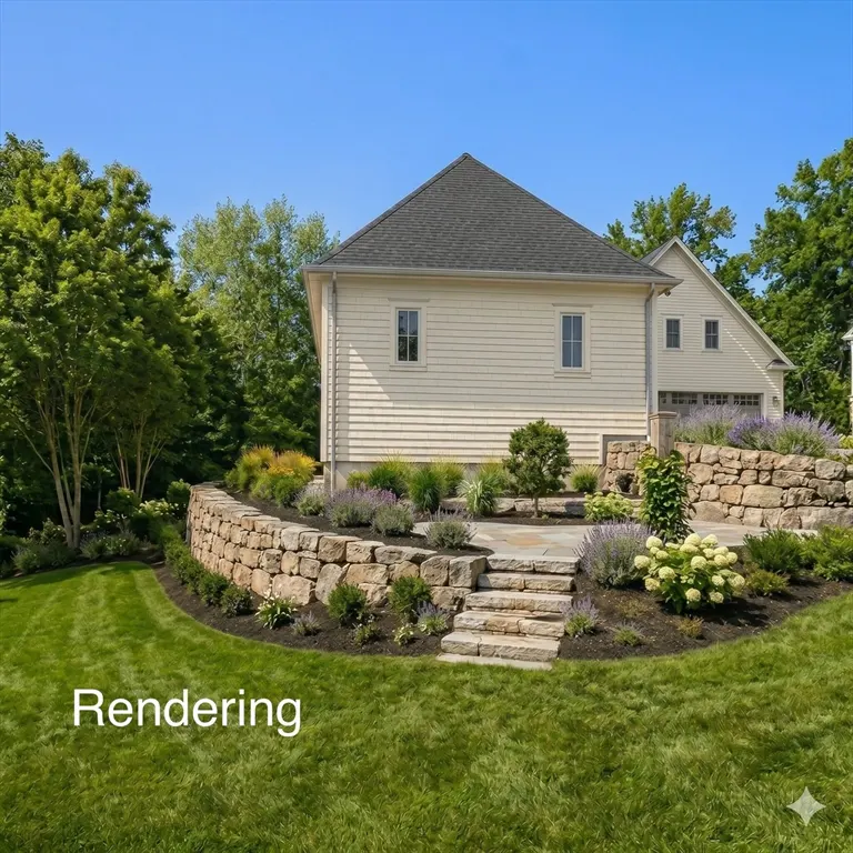 Backyard view of a beige house with a dark roof, stone retaining walls, and green lawn under a blue sky.