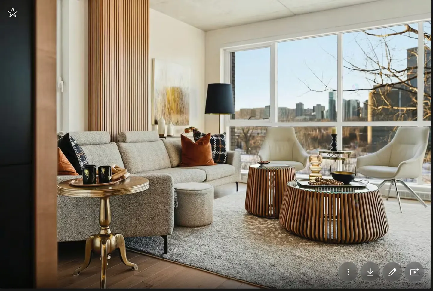 A bright living room with a gray sofa, wooden coffee tables, and a large window with a city view.