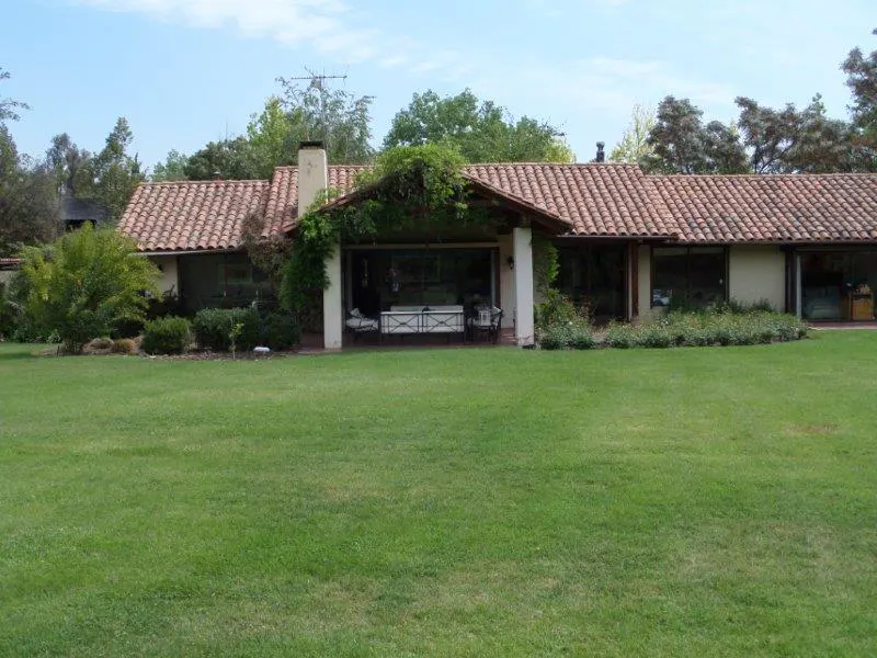 A single-story house with a red tile roof and a large green lawn.
