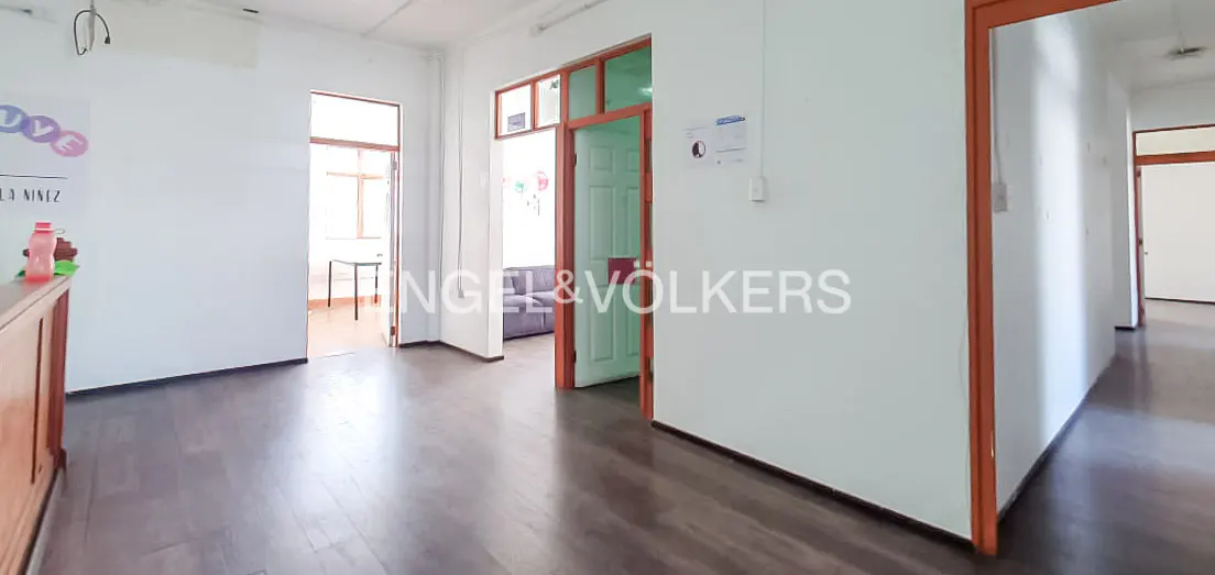 A bright office space with white walls, dark wood floors, and orange door frames.