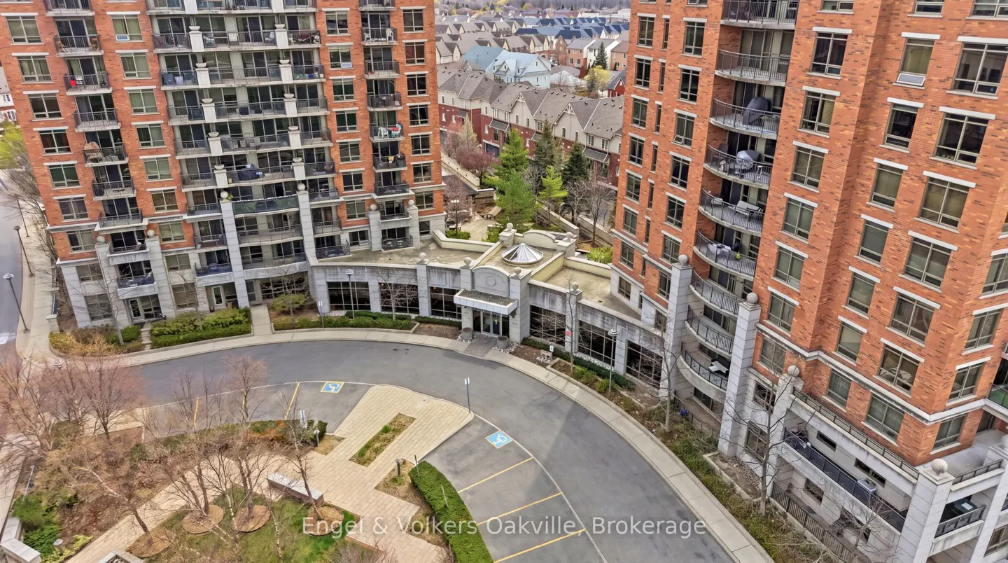 Aerial view of two tall brick apartment buildings with balconies, connected by a gray stone entrance and circular driveway.