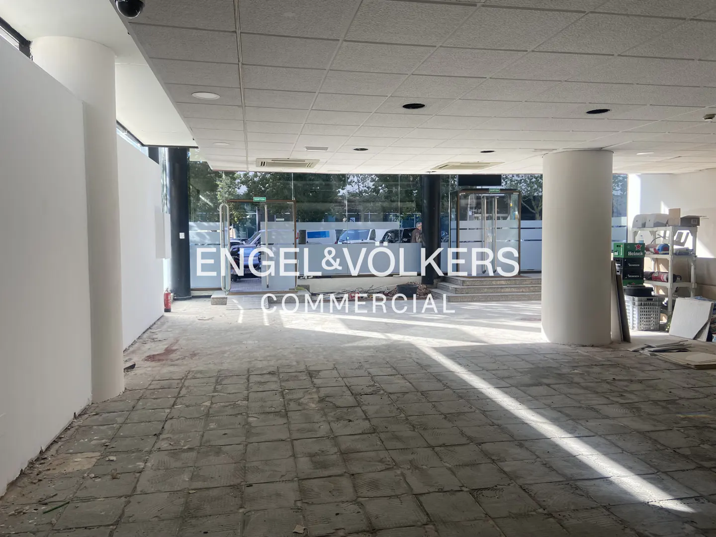 Interior view of a commercial space with white walls, tiled floor, and Engel & Völkers Commercial logo on the glass entrance.