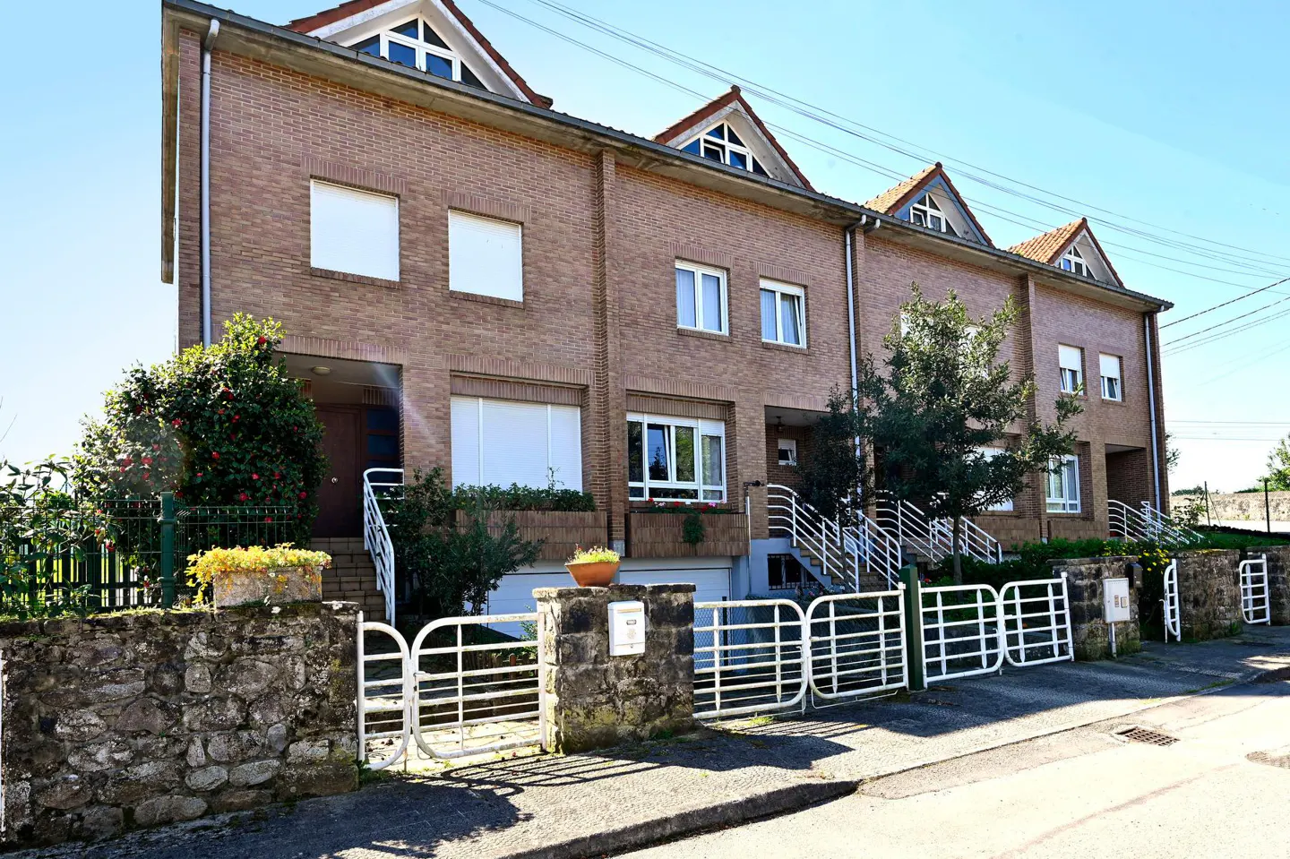 Three-story brick townhouses with white trim and gated entrances on a sunny day.