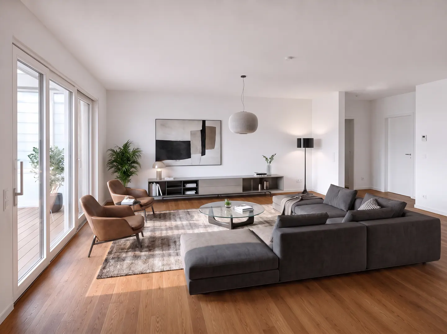 Modern living room with a grey sectional sofa, two tan leather chairs, a glass coffee table, and abstract wall art.