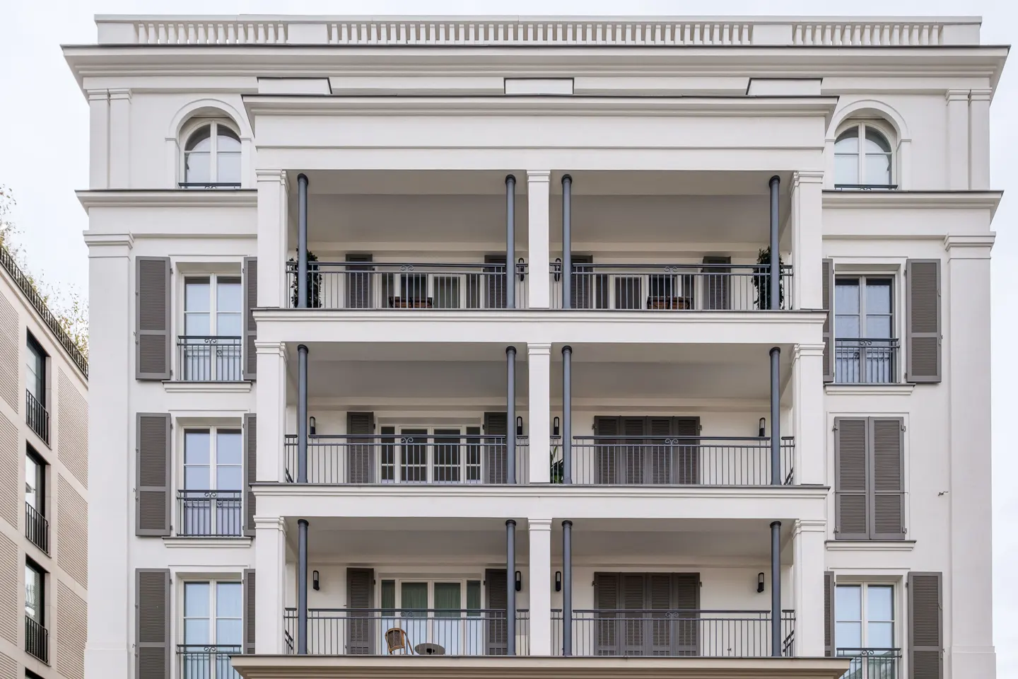 Exterior of a white apartment building with balconies and gray shutters.