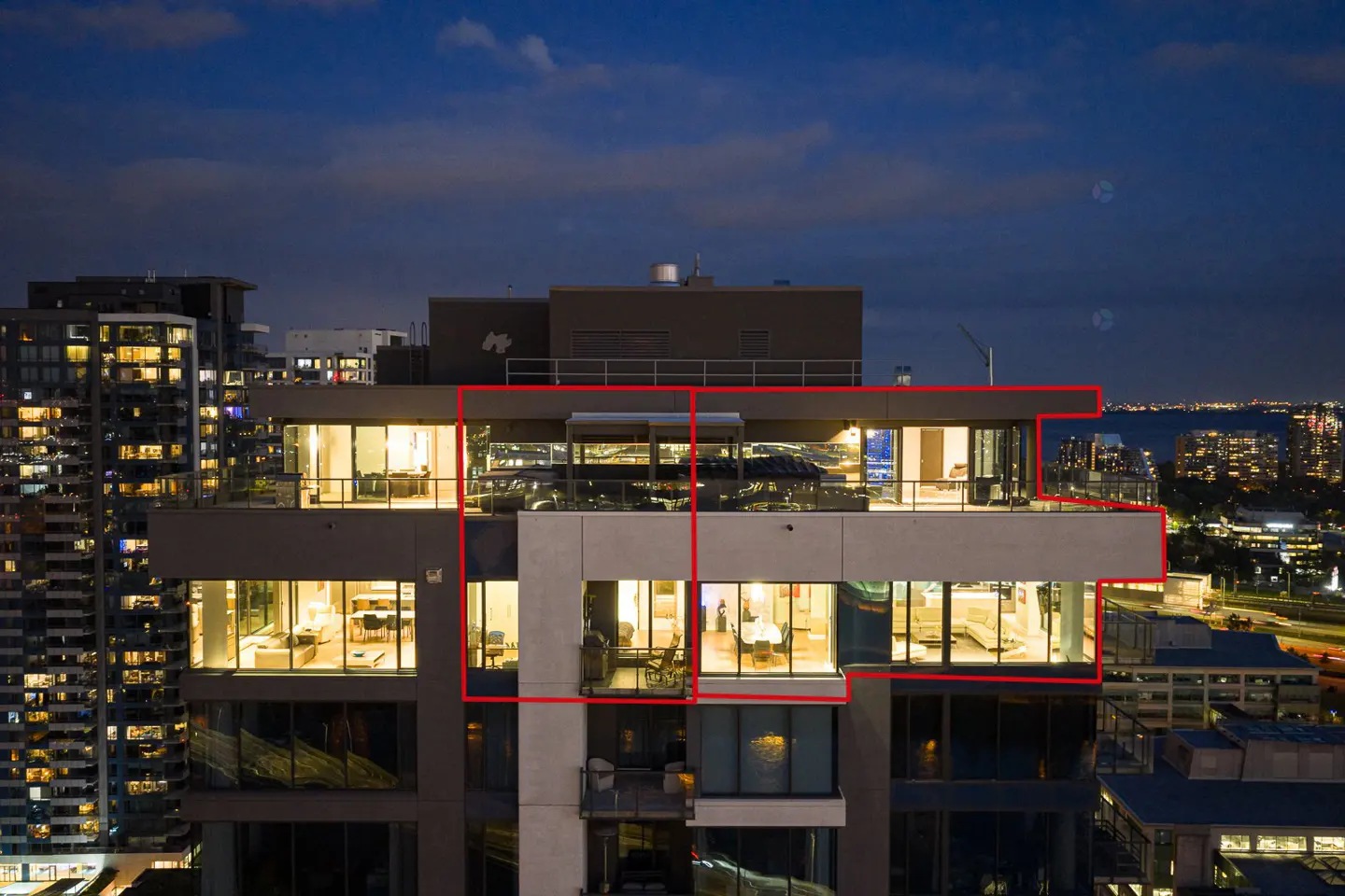 Exterior shot of a modern high-rise condo at night with city lights in the background.