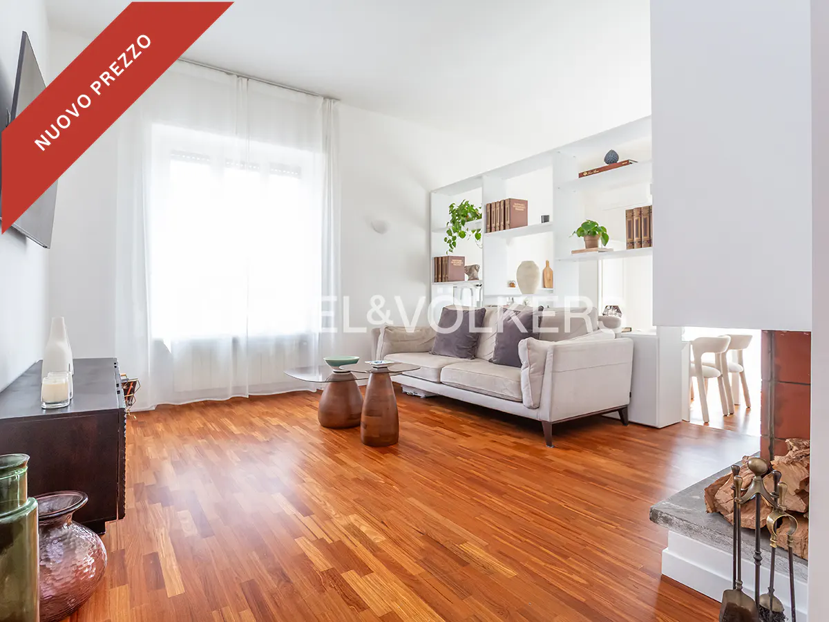 Bright living room with hardwood floors, a beige sofa, glass coffee tables, and built-in white shelving with decor.