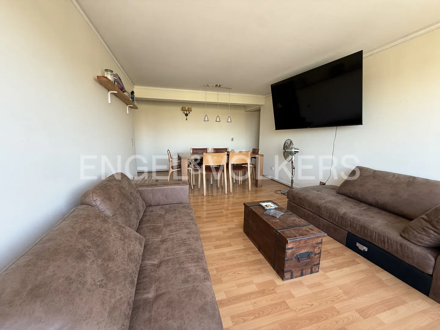 A living room with brown sofas, a wooden coffee table, and a dining table in the background.
