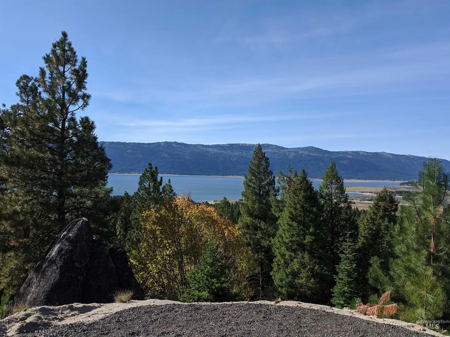 Scenic view of a lake surrounded by mountains and trees under a blue sky.