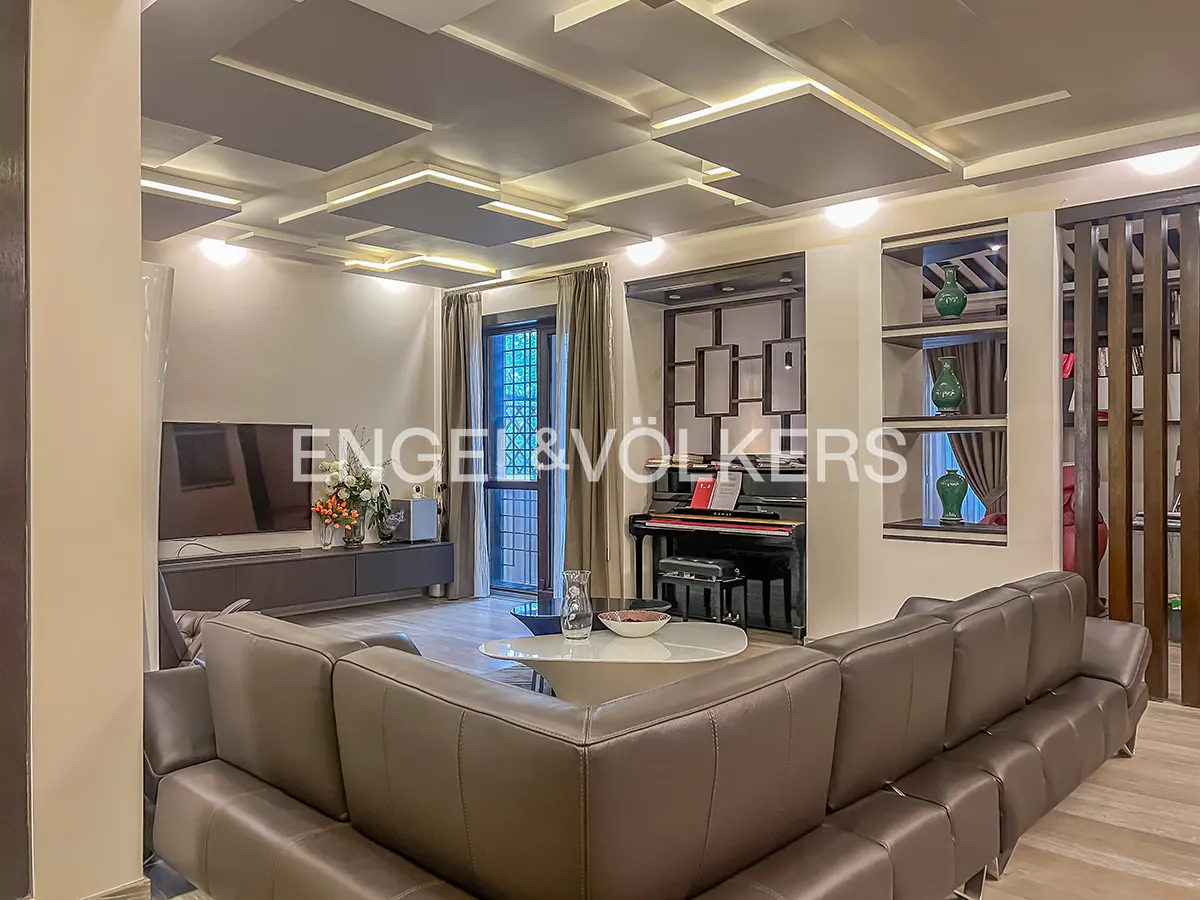 Living room with a brown leather sectional sofa, piano, TV, and modern ceiling lights.