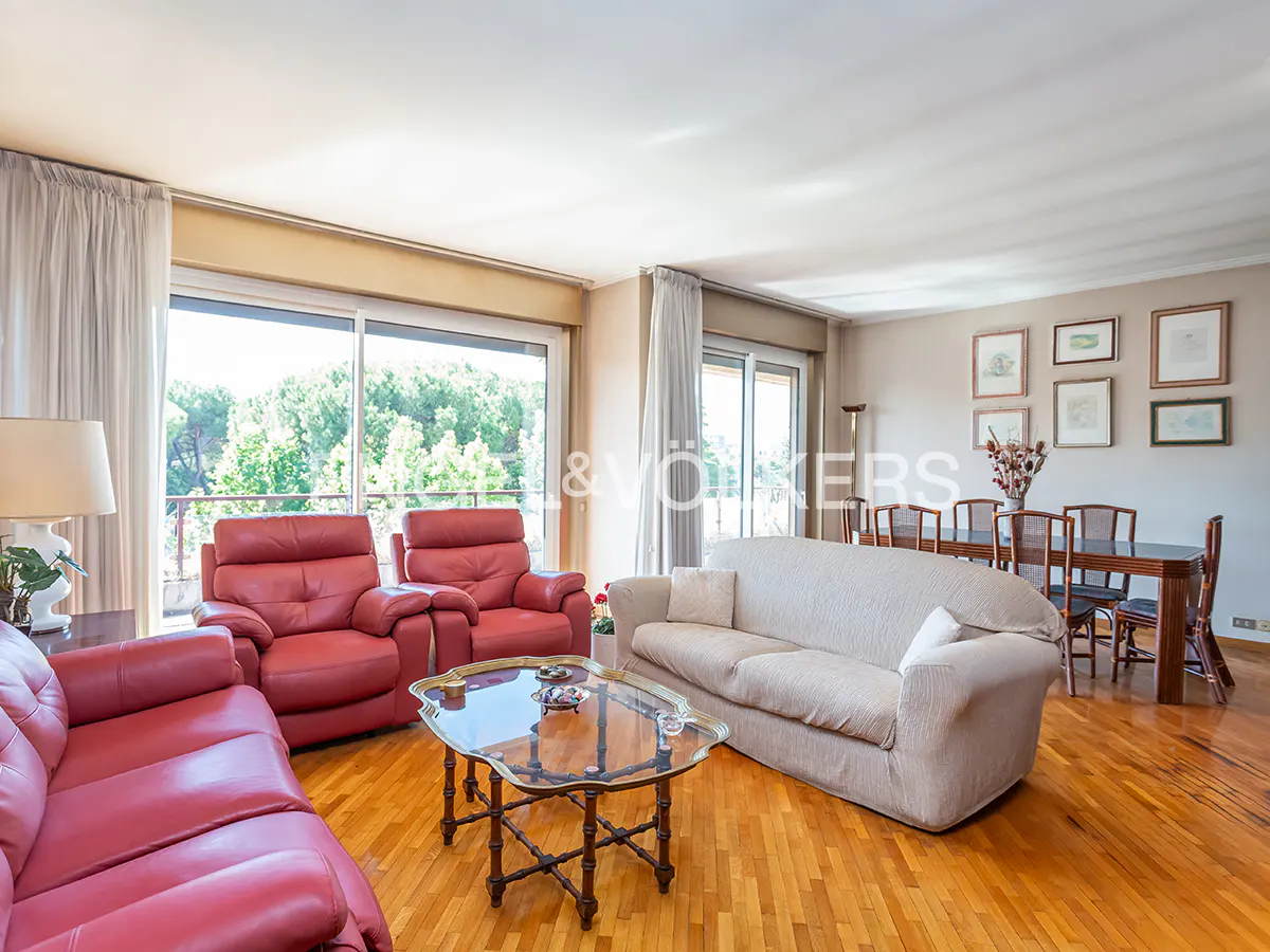 Bright living room with red leather sofas, a beige sofa, glass coffee table, and a dining area with wooden floors.