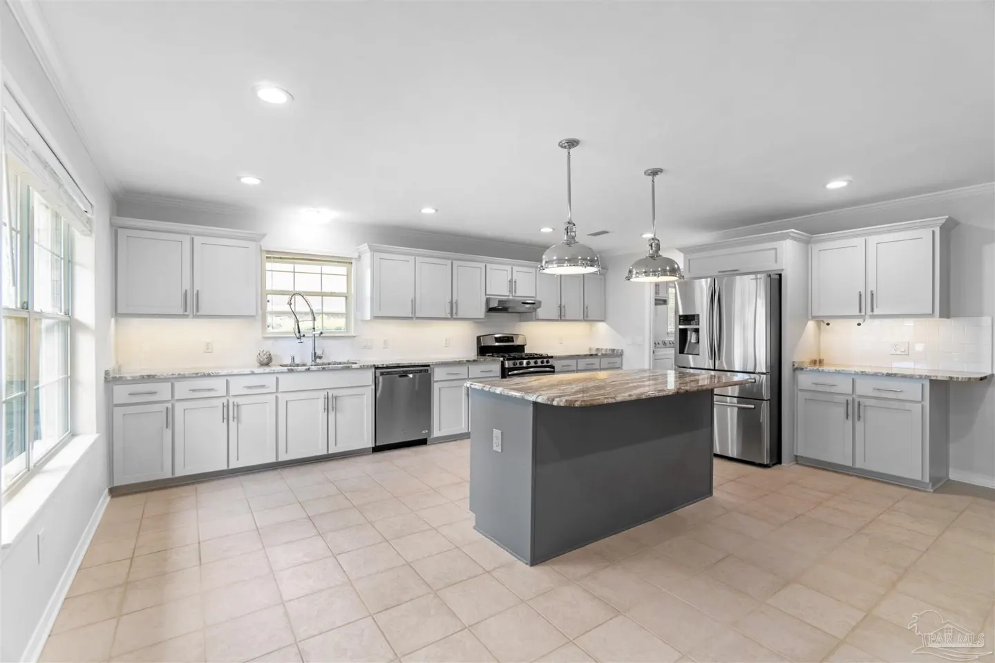 Modern kitchen with white cabinets, stainless steel appliances, a dark gray island, and tile flooring.