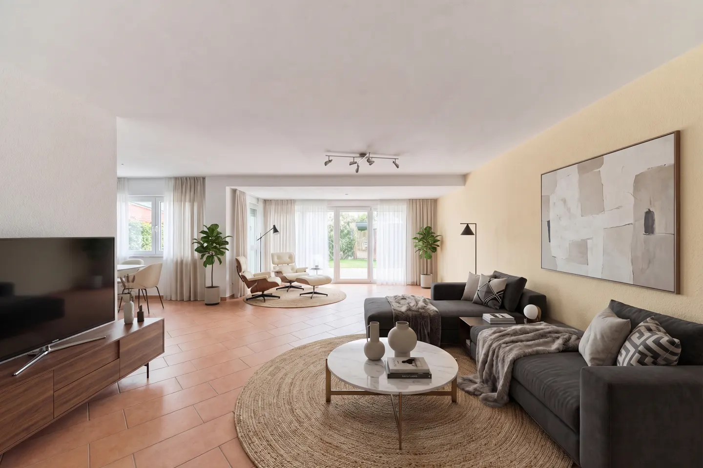 A bright living room with a gray sectional sofa, a round jute rug, and a marble coffee table. A TV and console are on the left.