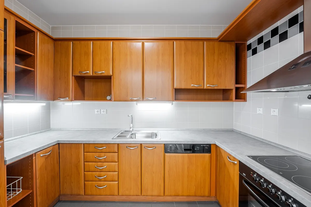 A kitchen with light brown wood cabinets, gray countertops, and stainless steel appliances.