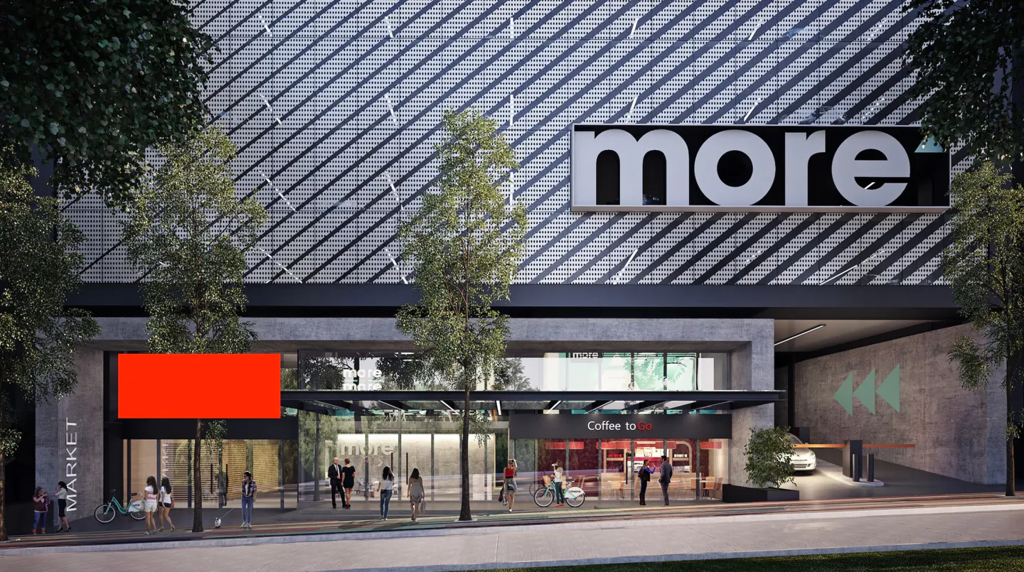 Modern building exterior with a "more" sign, a Coffee to Go shop, a parking entrance, and people walking on the sidewalk.