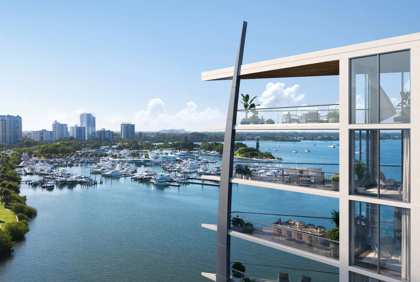 Condo building overlooking a marina. Balconies have plants and furniture. City skyline in the background. Blue sky.