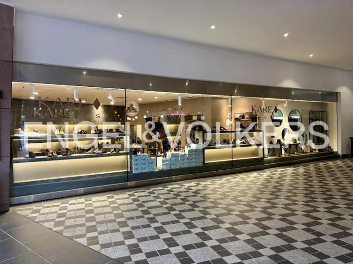 Storefront of Kare Shoes, an Engel & Volkers partner, with shoes displayed on shelves. The floor is a black and white checkered pattern.