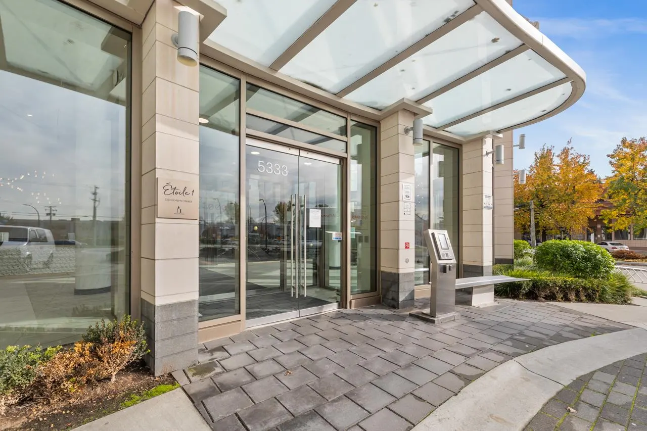 Exterior view of the building entrance with glass doors, address number 5333, stone pillars, and a glass canopy.