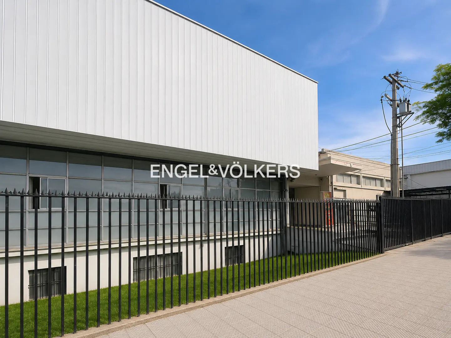 Exterior view of a white, two-story commercial building with black iron fencing and the Engel & Völkers logo.