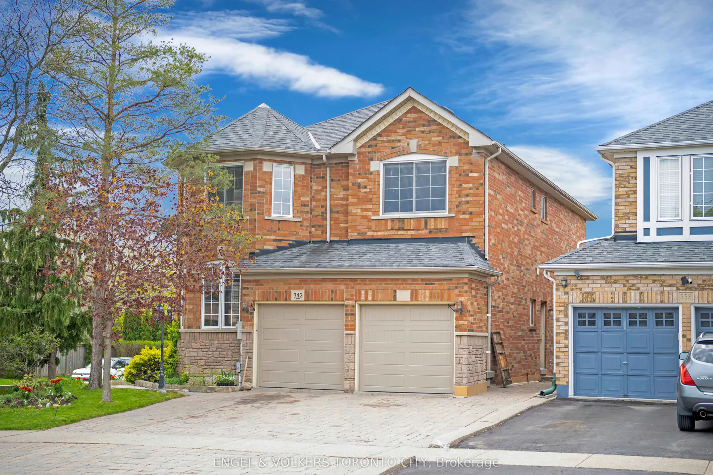 Two-story brick house with a gray roof, two-car garage, and a blue sky background.