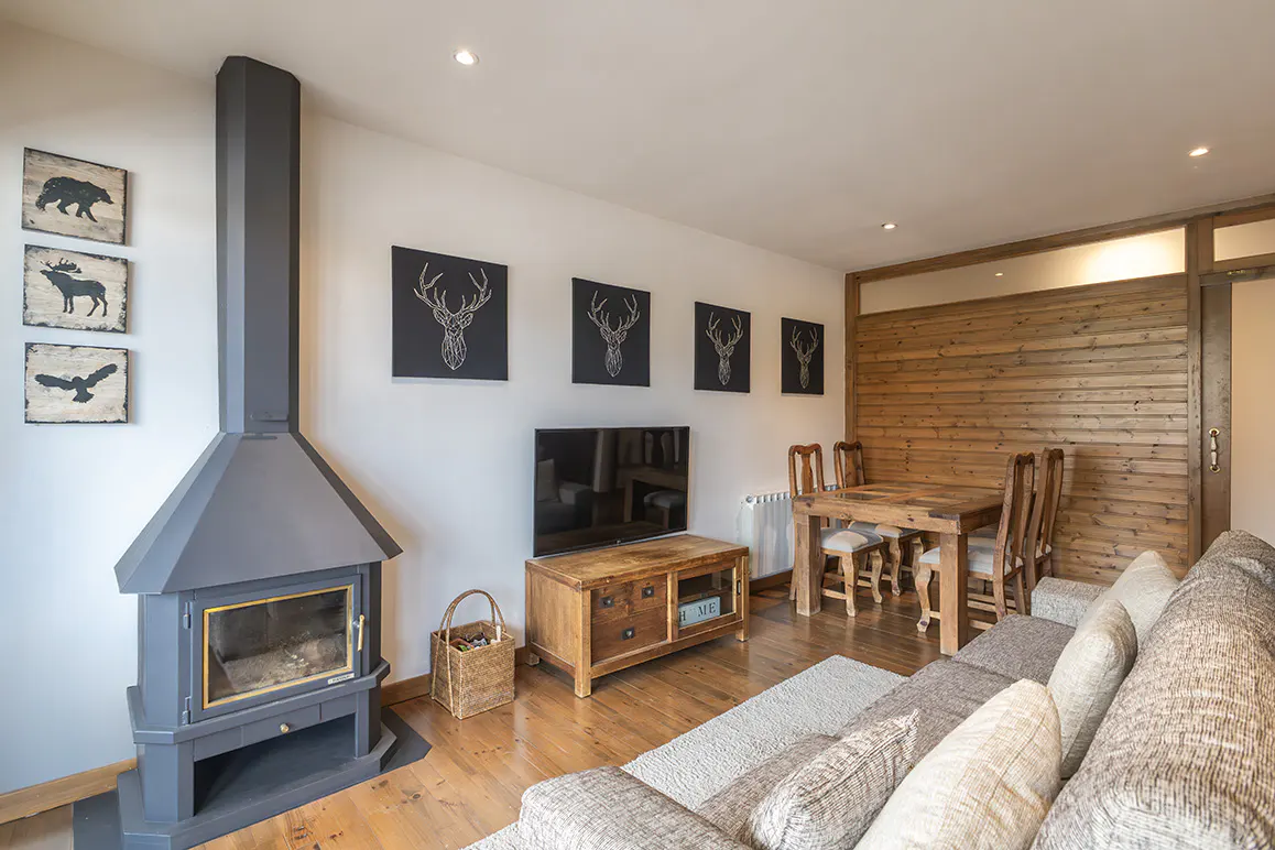 Living room with a gray fireplace, wood floors, and a dining table. Animal art hangs on the white walls.