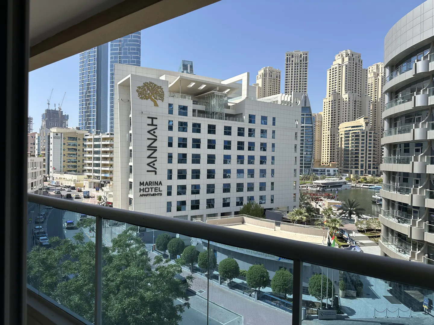View from a balcony overlooking the Jannah Marina Hotel and Dubai skyline on a sunny day.