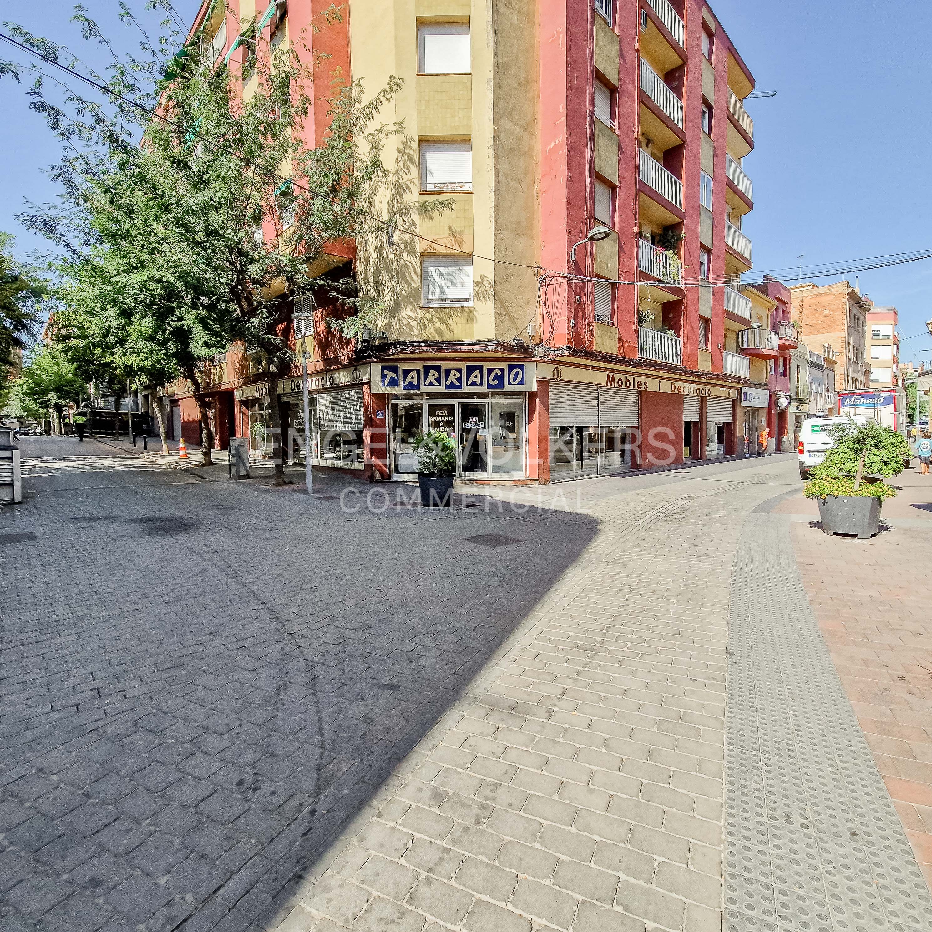 Corner view of a red and yellow apartment building with a ground-floor furniture store on a paved pedestrian street. [AI-generated text]