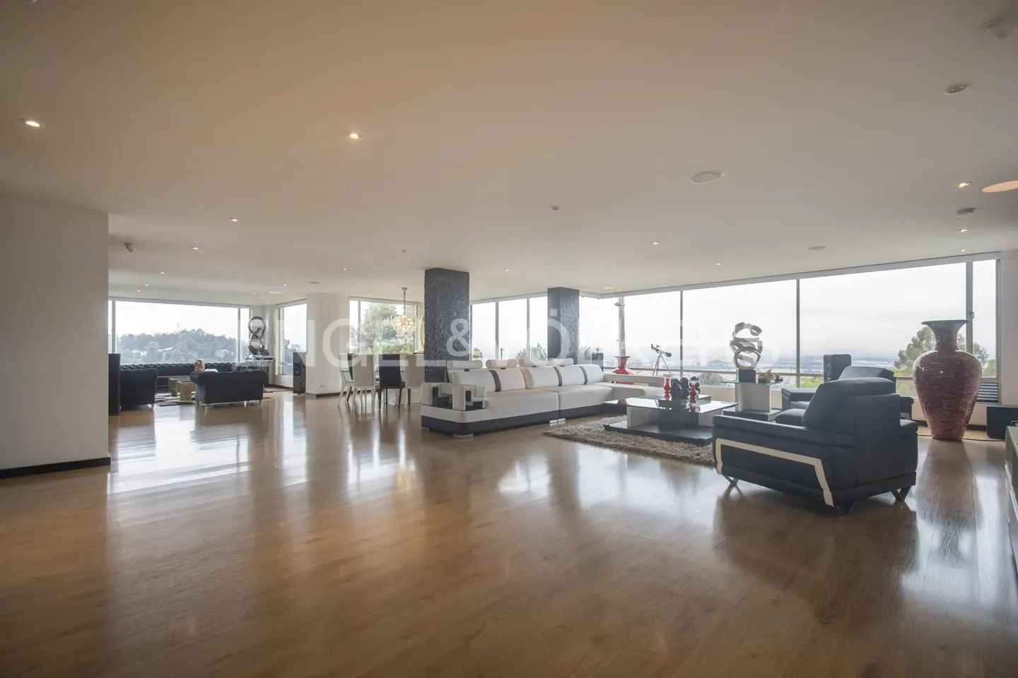 A spacious living room with hardwood floors, floor-to-ceiling windows, and modern furniture.