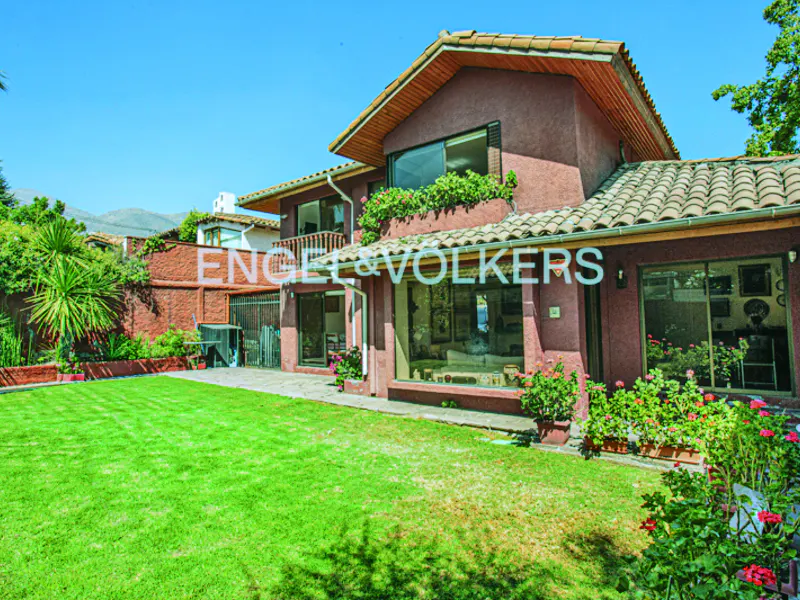 Two-story house with a red exterior, brown roof, green lawn, and Engel & Volkers logo on the window.