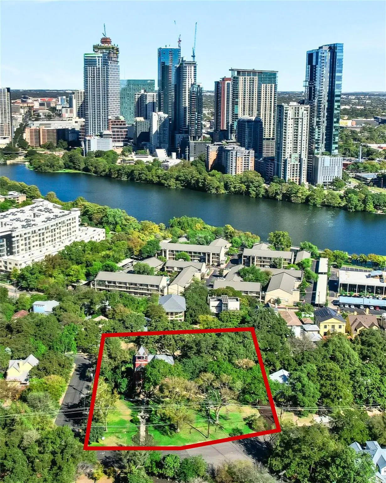 Aerial view of a property outlined in red, with Austin, Texas skyline and a river in the background.
