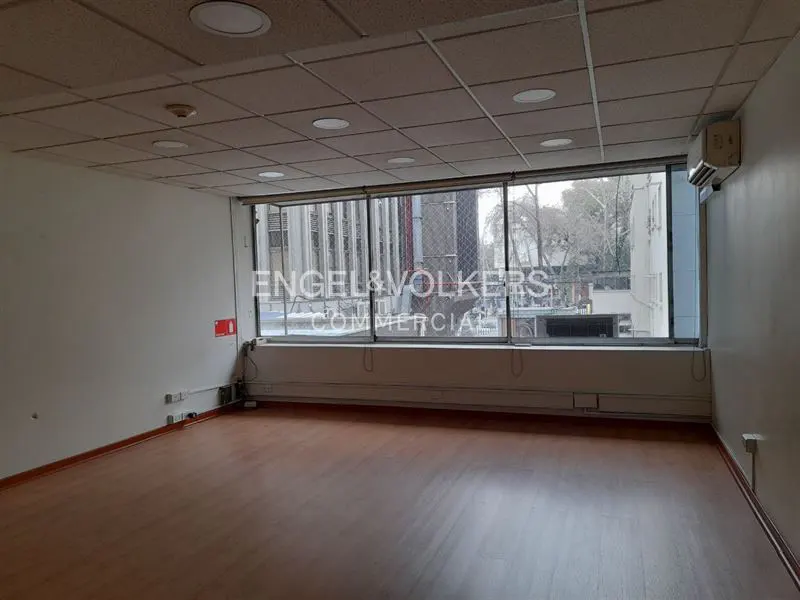 Empty office space with wood floors, white walls, and a large window with the Engel & Volkers logo.