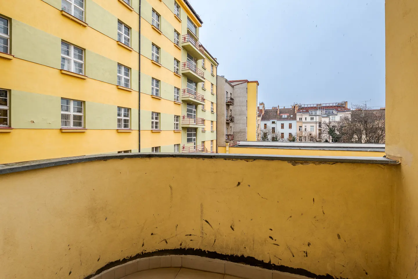 View from a yellow balcony overlooking a city with yellow and green buildings.